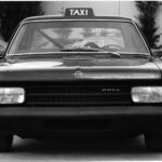 Als der Rekord C erschien, war die Taxi-Farbe in Deutschland noch Schwarz. So montierten die Opel-Designer als Gag der „Schwarzen Witwe“ auch einmal ein Taxi-Schild. Im Hintergrund ist das neue Opel Rekord C Coupé zu sehen.
